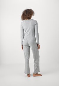 Ensemble de loungewear gris à côtes comprenant un haut à manches longues avec un ourlet festonné et un pantalon assorti à coupe évasée avec un bord effiloché.