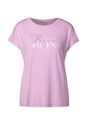 T-shirt à manches courtes rose clair en tissu doux avec "BON" en texte blanc et argenté, accompagné d'un accent courbé sur les lettres.