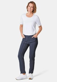 Witte shirt met korte mouwen, navyblauwe gestreepte broek en witte sneakers. De broek heeft zakken en een getailleerde pasvorm. Schoon en eenvoudig ontwerp.