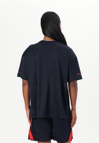 Navy blue mesh t-shirt with short sleeves, loose fit, featuring a subtle textured pattern and a red accent on the sleeve.