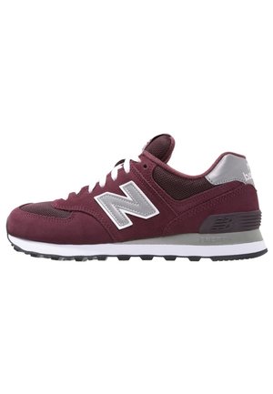 Zapatilla New Balance granate y gris con cordones blancos, parte superior de malla y ante, y suela acolchada con dibujo negro.