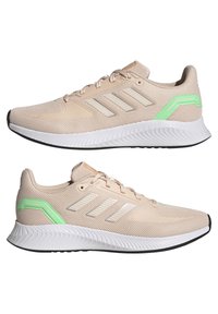 Scarpe da ginnastica beige con tomaia in rete, strisce riflettenti argento e accenti verdi. Presentano una suola intermedia bianca imbottita e suola nera.