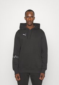 Mustapaita, jossa on säädettävä huppu, kengurupocket ja Puma-logo. Vasemmassa hihassa on harmaa sahalaitakuosi.