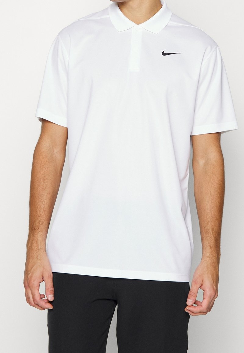 Polo-shirt blanc en tissu lisse. Il dispose d'une patte de boutonnage à trois boutons, de manches courtes et d'un petit logo noir du côté gauche.