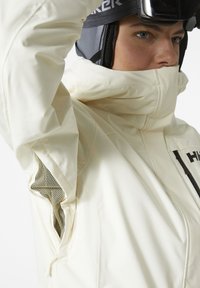 Witte waterdichte skijas met een hoge kraag, mesh ventilatie en opvallende ritszakken. Gemaakt van glad, duurzaam materiaal.