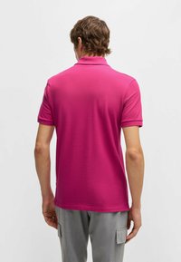 Kortärmad polo t-shirt i stark rosa, med klassisk krage och en mjuk bomullstextur, designad med en skräddarsydd passform.