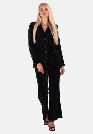Black velvet suit with a tailored blazer and matching flared trousers. Features smooth texture, five buttons, and side pockets.
