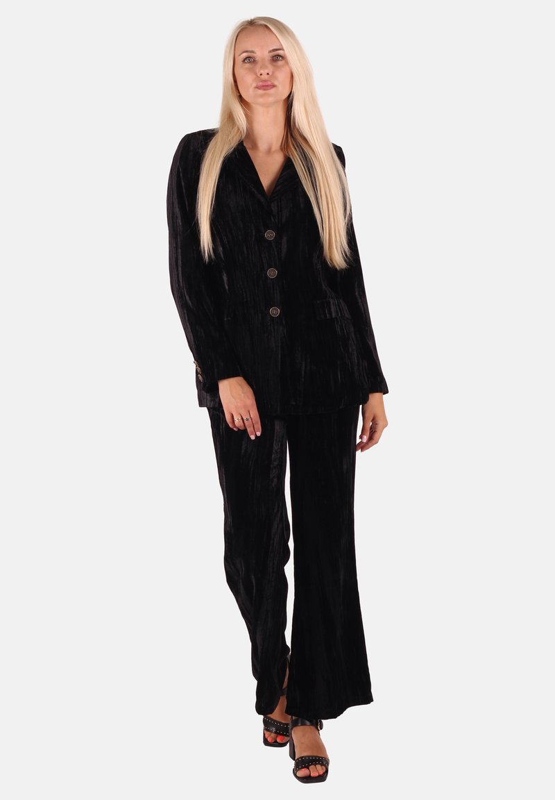 Black velvet suit with a tailored blazer and matching flared trousers. Features smooth texture, five buttons, and side pockets.