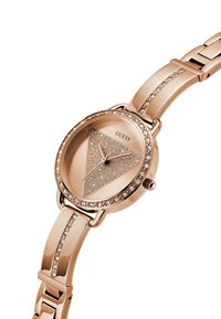 Reloj de oro rosa con una carátula triangular brillante, acentos de cristal en una pulsera de eslabones y un acabado metálico suave.