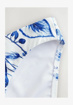 Bikiniunderdel i vitt tyg med blå blommönster. Har en mjuk textur, rundade kanter och kontrasterande blå sömdetaljer.