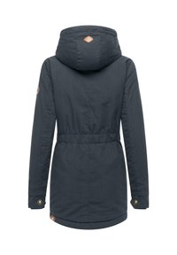 Musta sininen, vyötärönpituinen takki, jossa on huppu, joustava vyötärö, pitkät hihat ja napitettavat rannet. Huomattava logo takana lähellä huppua.