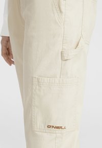Beige cargo pants made of durable fabric feature a side pocket and subtle O'Neill logo in brown thread near the lower waist.