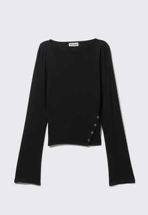 Haut noir à manches longues avec encolure bateau et trois petits œillets argentés disposés en diagonale près de l'ourlet inférieur du côté droit.