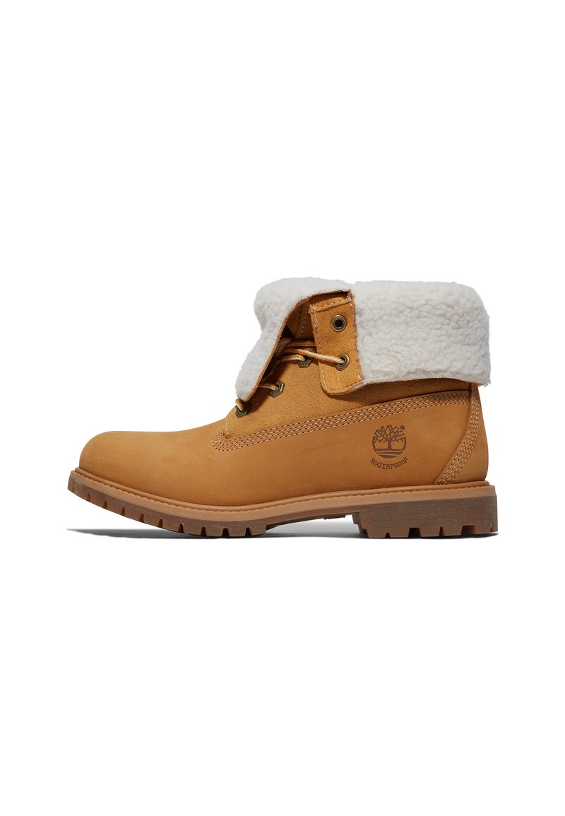 Botte en suède marron avec un revers en fausse fourrure blanche, bout rond et semelle en caoutchouc à motifs. Présente des œillets dorés et un logo sur le côté.