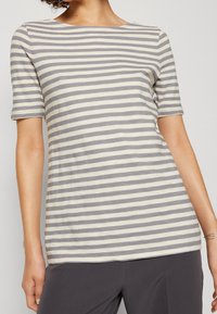 Camiseta a rayas en gris y crema, con escote redondo y mangas cortas, fabricada en suave algodón con un corte relajado.