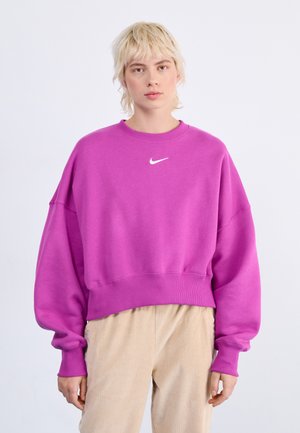 Fialová skrátená mikina s dlhými rukávmi a okrúhlym výstrihom; na hrudníku sa nachádza biele logo Nike; mäkká, štruktúrovaná tkanina.