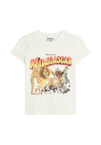 Vit bomulls T-shirt med en färgglad grafisk tryck av karaktärer från "Madagaskar", inklusive djur och titeln i fet stil.