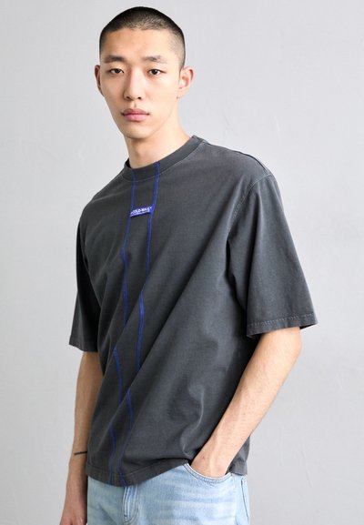 Gray short-sleeve t-shirt made of cotton, featuring blue stitching along the front and a small logo label on the chest.