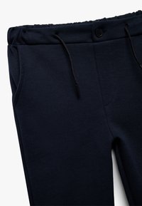 Marineblå joggerbukser lavet af struktureret stof, med elastisk talje, snøredetalje og sidelommer.
