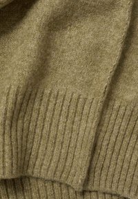 Tessuto a maglia verde oliva con una texture morbida, caratterizzato da dettagli a coste ai bordi, che mostrano variazioni nello spessore del filato.