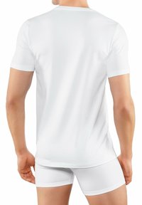 T-shirt bianco in cotone a maniche corte, con design a girocollo. Texture liscia, silhouette aderente, indossato con boxer bianchi.