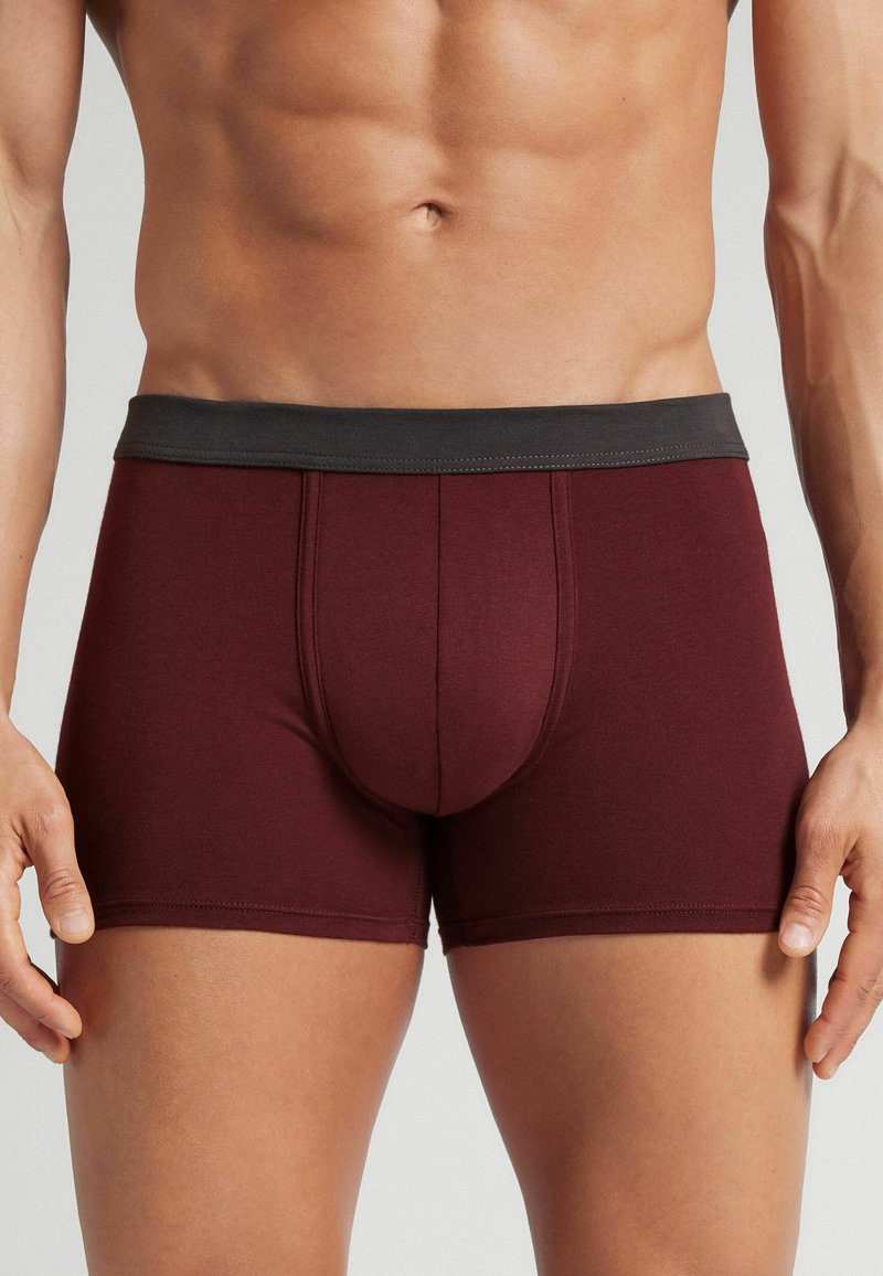 Vinröda boxerkalsonger med grå midjeband, som har en framficka och stickade detaljer. Tillverkade av mjukt, elastiskt tyg.