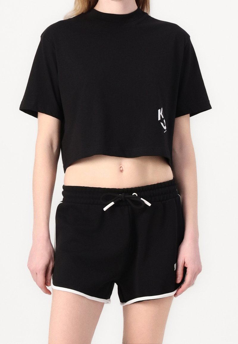 Svart kortärmad t-shirt i mjukt tyg, med korta ärmar och en liten logotyp. Matchas med svarta shorts med vit kant och dragsko.