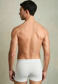 Boxeri albi din bumbac cu un band elastic, prezentând un branding subtil. Textură netedă și design ajustat, expus din spate.
