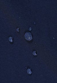 Marine stof met een gladde textuur, waarop verschillende waterdruppels zichtbaar zijn, wat wijst op waterafstotende eigenschappen.