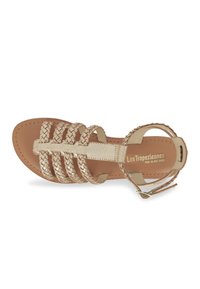 Sandalen met banden in lichtbeige leer met geweven accenten en een platte zool. Verstelbare enkelband met metalen hardware.