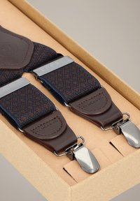 Brązowo-granatowe szelki we wzory z srebrnymi klipsami. Skórzane elementy przy klipsach. Zapakowane w tekturowe pudełko kraftowe.