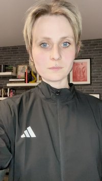 Veste de sport noire avec un col haut, arborant un logo à trois bandes blanches sur la poitrine gauche et une texture lisse et mate.