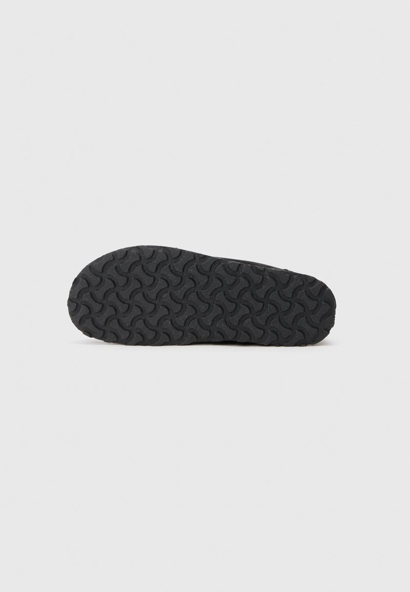 Suela de zapato de goma negra con una superficie texturizada que presenta un patrón de banda de rodadura ondulado para tracción y agarre.