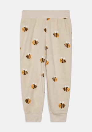 Bløde beige børnebukser med smilende bie-mønstre over det hele, elastisk talje og manchetter ved anklerne.