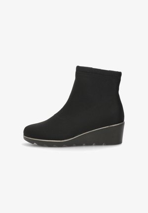 Botín negro con parte superior de textil suave, tacón de cuña y punta redondeada. Presenta un sutil acento metálico a lo largo del borde de la suela.