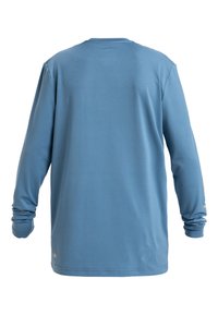 Långärmad skjorta i mjukt, ljusblått tyg. Har en klassisk rund halsringning och åtsittande ärmar, med en liten varumärkesetikett nertill.