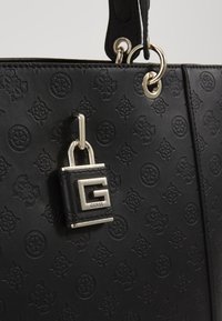 Schwarze Handtasche mit einem geprägten Muster, ausgestattet mit einem silbernen Vorhängeschloss und Logo-Akzent. Aus Leder gefertigt, mit stabilen Griffen und strukturiertem Design.