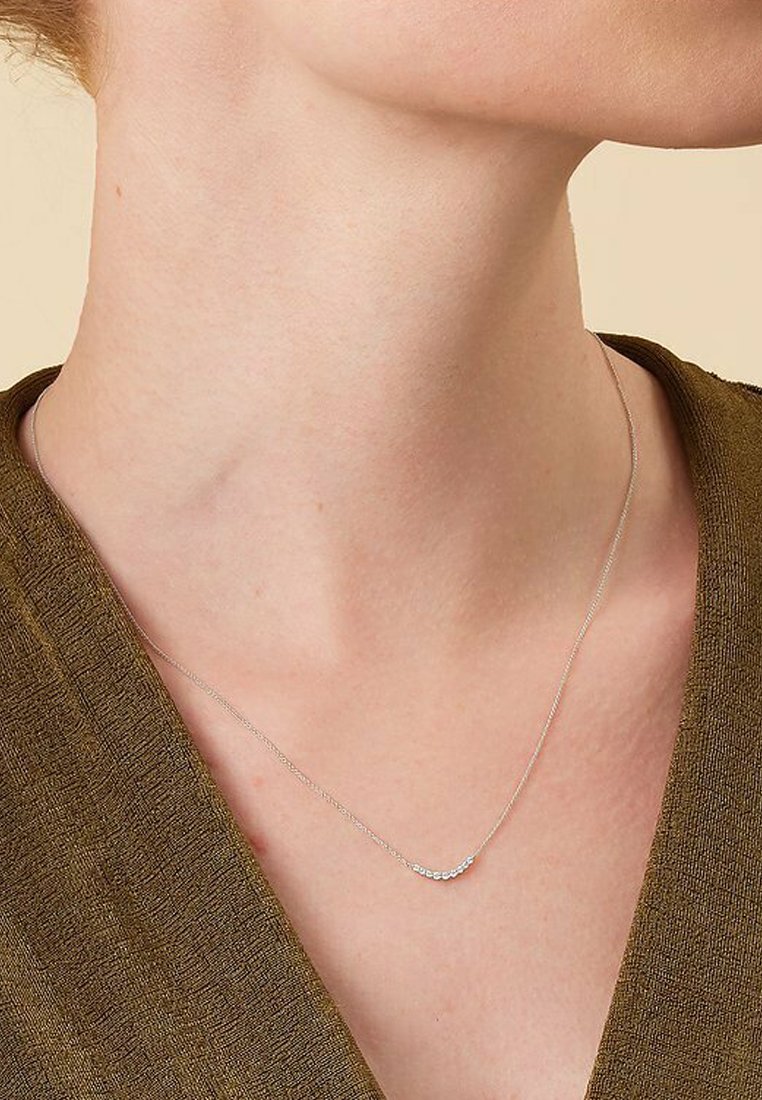 Silberne Halskette mit einem zarten, geschwungenen Design, das kleine, schimmernde Steine auf der Vorderseite zeigt. Die Kette ist fein und minimalistisch.