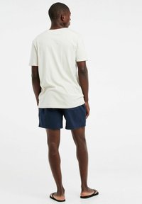 Lichtbeige katoenen t-shirt en marineblauwe shorts. Het t-shirt heeft een relaxte pasvorm en korte mouwen, terwijl de shorts knielang zijn met zakken.