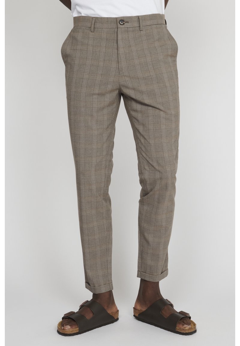 Bruna rutiga byxor i ett lätt material med smal passform, veckad front och uppvikta benslut, samt mörkbruna sandaler med öppna tår.