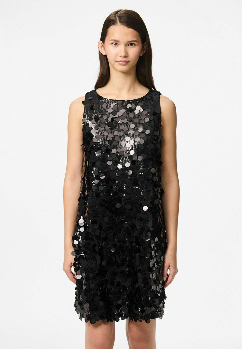 Crna haljina bez rukava prekrivena kružnim šljokicama, koja stvara reflektirajući tekstur. Haljina ima okrugli izrez i ravnu siluetu.