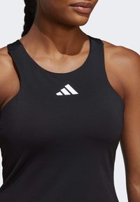 Zwarte sportieve tanktop met een ronde halslijn en brede schouderbanden; voorzien van een wit Adidas-logo op de borst. Glad, aansluitend materiaal.