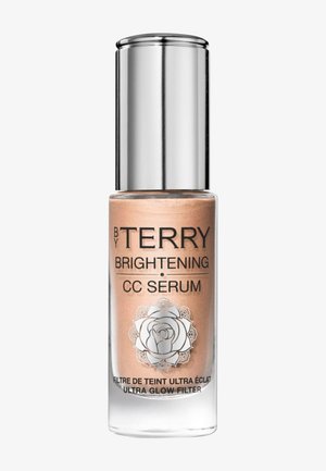 Glasflasche des By Terry Brightening CC Serums mit silberner Kappe und floralem Logo, mit der Aufschrift Ultra Glow Filter, auf weißem Hintergrund.