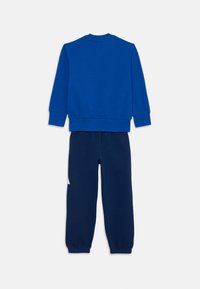 Blue sweatshirt with crew neck and long sleeves paired with navy sweatpants featuring elastic cuffs and a white label on the leg.