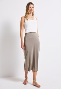Skimrande beige midikjol med en åtsittande midja, sidoklyfta, mjukt material, ihop med en vit tanktop och sandaletter med remmar.