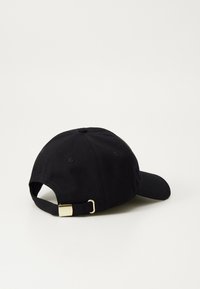 Cap em algodão preto com aba curva, apresentando uma fivela de metal dourada na correia ajustável e detalhes de costura sutis na superfície.
