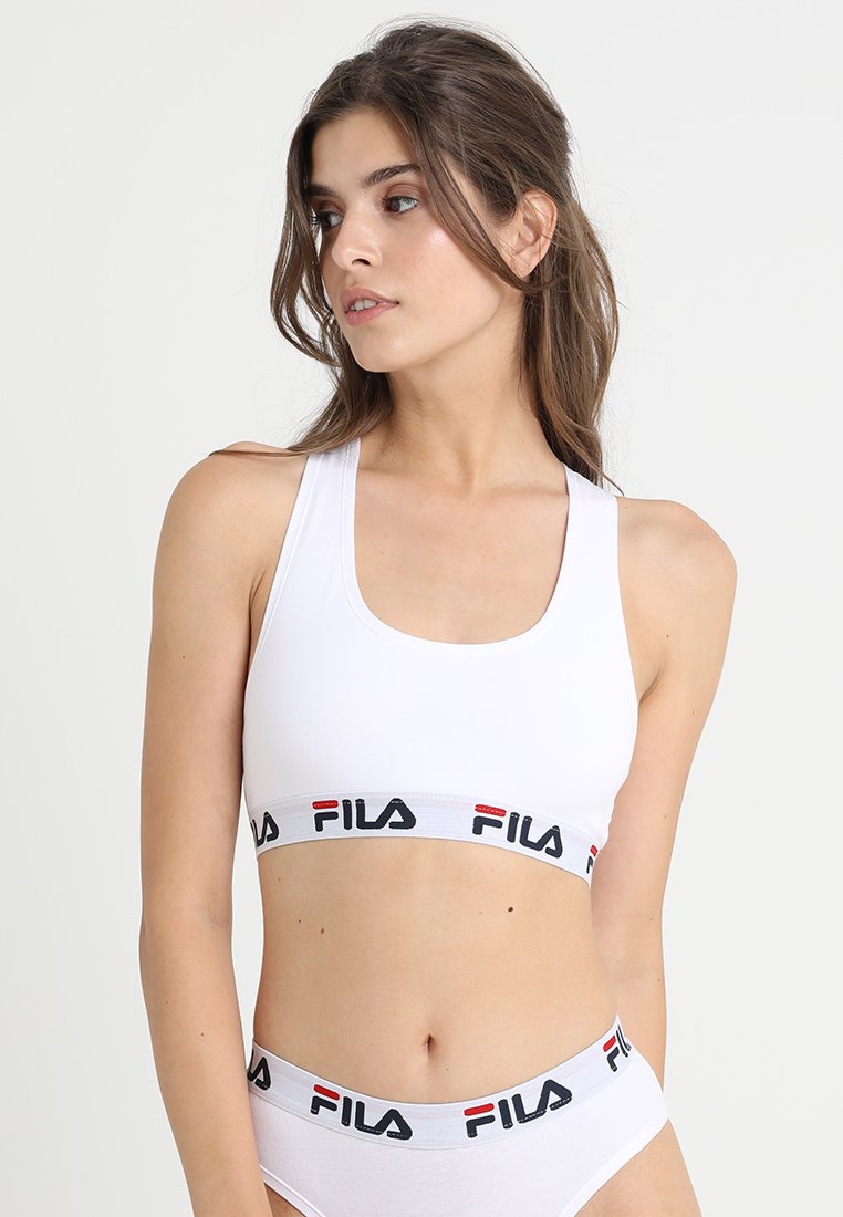 Hvit treningstop med bred svart og rød FILA-merket stropp. Har en scoop neckline og tykke skulderstropper. Glatt, elastisk stoff.