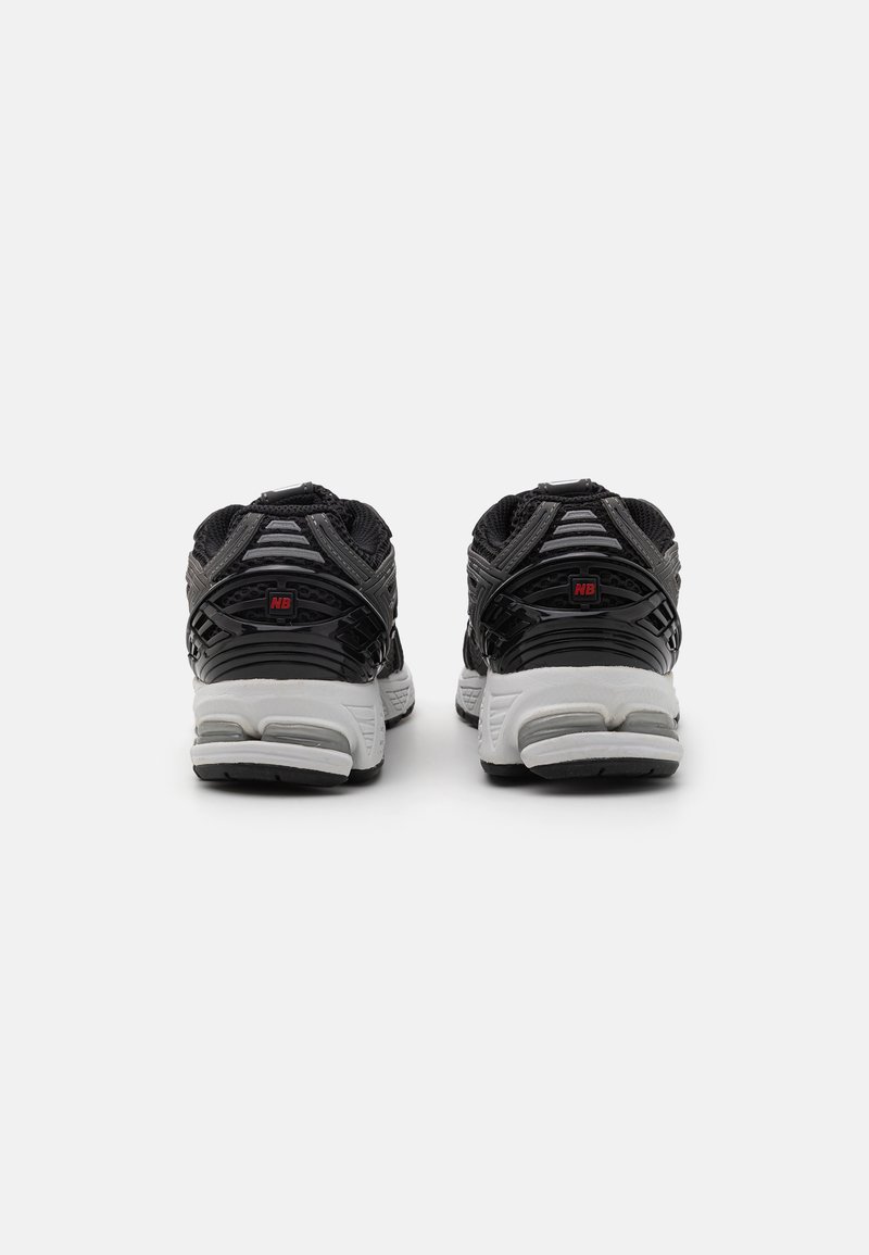 Zapatos deportivos negros con un upper texturizado, acentos grises y una suela blanca. Presentan un talón pronunciado y un diseño de entresuela acolchada.