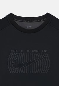 Μαύρο αθλητικό μπλουζάκι Nike με στρογγυλή λαιμόκοψη και κοντά μανίκια. Στο μπροστινό μέρος αναγράφεται "ΔΕΝ ΥΠΑΡΧΕΙ ΤΕΛΙΚΗ ΓΡΑΜΜΗ" και το λογότυπο σε τονική σχεδίαση.