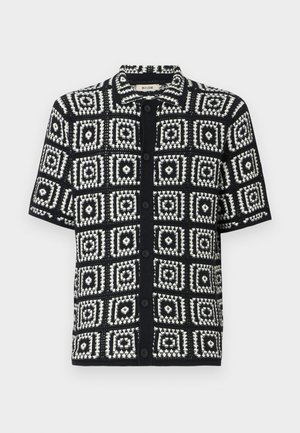 Krátky rukáv košele v čiernej a bielej farbe so štvorcovým vzorom. Vyrobené z textúrovanej látky, s gombíkovým zapínaním a špicatým golierom.